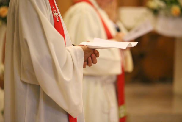 sacerdote con le mani unite nella preghiera durante la santa messa in chiesa - cattolicesimo foto e immagini stock