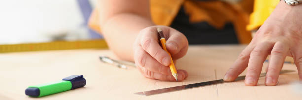 istock Arms of worker making structure plan on scaled paper closeup 1073611616