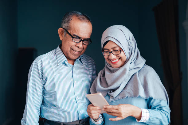 Senior Asian Couple Looking at Smartphone Lifestyle Interactions malay couple stock pictures, royalty-free photos & images