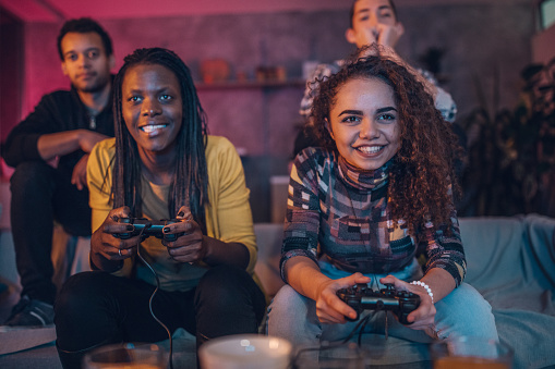 Group of multi ethnic people, friends sitting at home, playing video games.