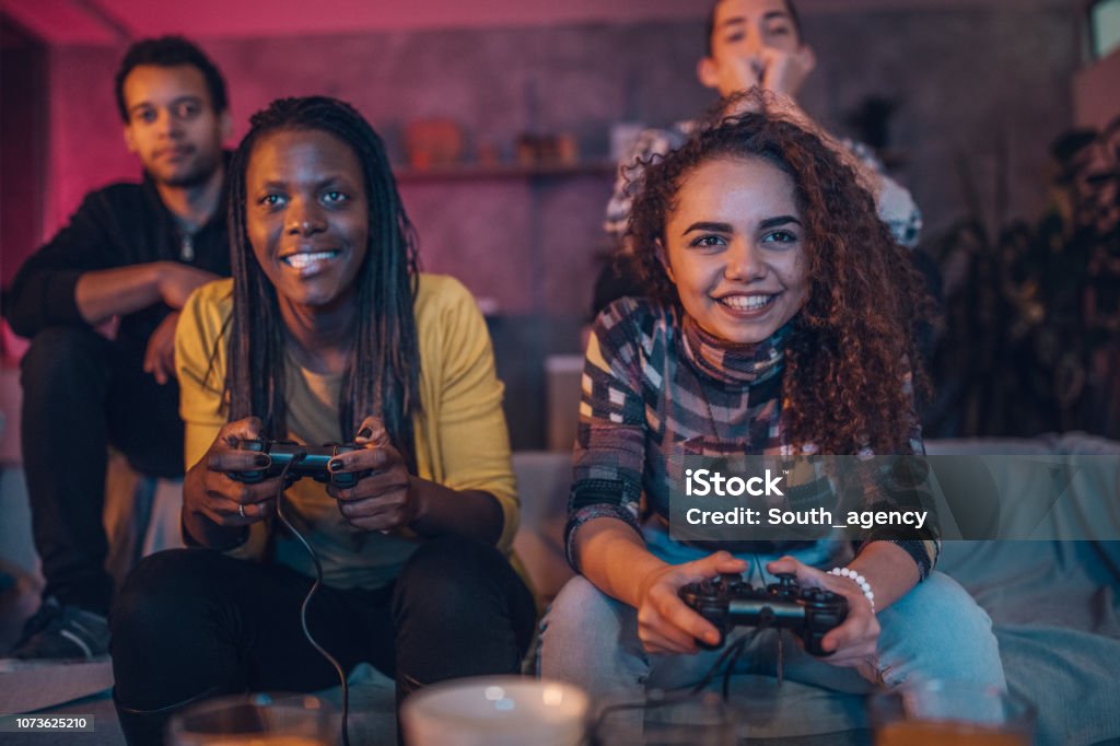Friends love video games Group of multi ethnic people, friends sitting at home, playing video games. Video Game Stock Photo