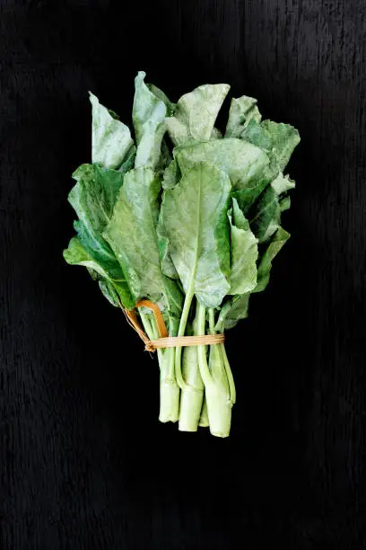 Photo of Chinese kale vegetable on the back wood background.