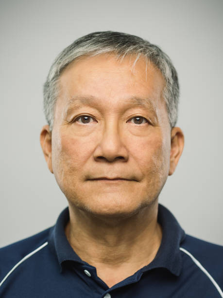 Real chinese senior man with blank expression Close up portrait of senior asian man with blank expression against gray background. Vertical shot of real chinese man staring in studio with gray hair. Photography from a DSLR camera. Sharp focus on eyes. patience photos stock pictures, royalty-free photos & images