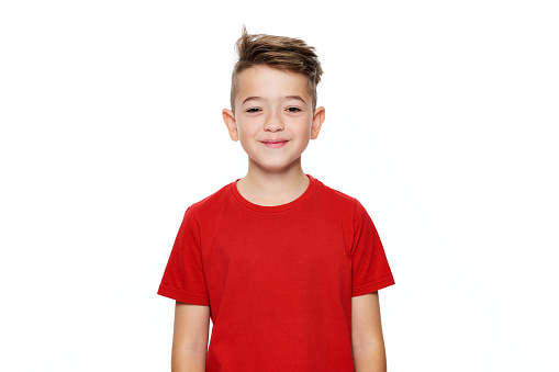 Adorable young teenage boy waist up studio portrait isolated over white background. Handsome boy looking at camera with cheeky smile.