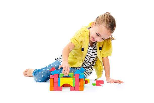молодая девушка строит замок с деревянным игру игрую блок. концепция детской игровой терапии на белом фоне. - block child play toy стоковые фото и изображения