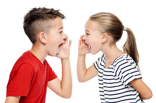 Young children facing eachother and shouting. Speech therapy concept over white background.