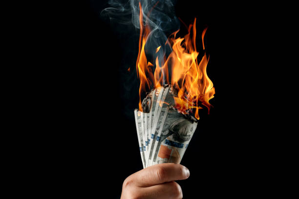 istock Male hand close-up, holds burning money in hands, burning US dollars. Black background, isolate. The concept of inflation, a decrease in the purchase of foreign currency, and devolution. 1073648518