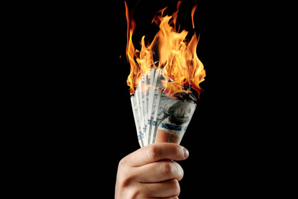 istock Male hand close-up, holds burning money in hands, burning US dollars. Black background, isolate. The concept of inflation, a decrease in the purchase of foreign currency, and devolution. 1073648550