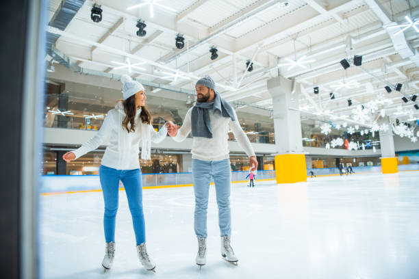 istock happy couple holding hands while skating on rink together 1073652954