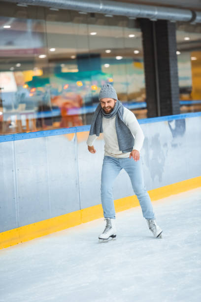 istock bearded man in knitted hat and sweater skating on ice rink 1073653152