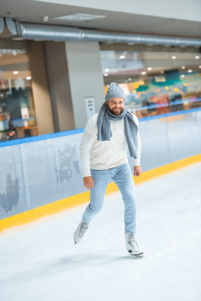 istock bearded man in knitted hat and sweater skating on ice rink 1073653178