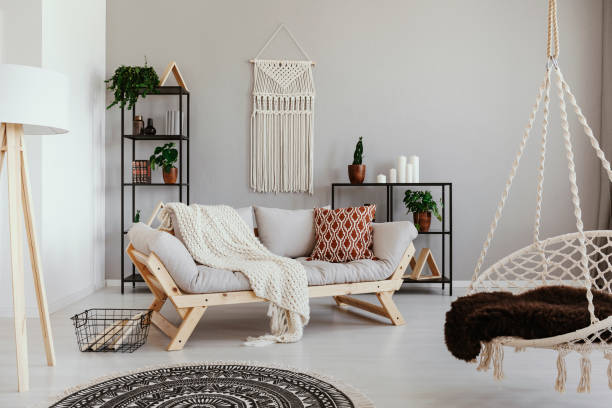 istock Handmade macrame on the empty wall of bright beige living room with comfortable couch with pillows and white blanket , real photo 1073655768