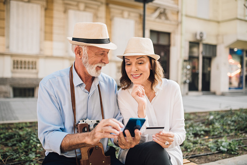 Senior couple of tourists shopping online with a phone and credit card