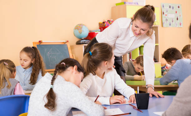 istock Teacher and pupils working in classroom at elementary school 1073667680