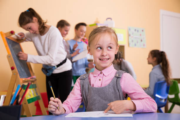 istock Happy little schoolgirl drawing during break 1073667734
