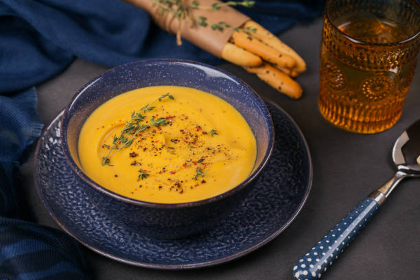 istock Pumpkin soup in blue bowl topped with fresh herb 1073668010