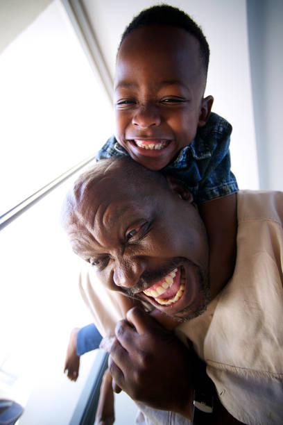 istock Grandfather playing having fun with son on his back indoors vertical 1073672876