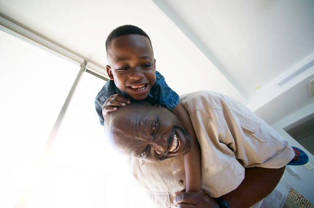 istock Grandfather playing having fun with son on his back indoors smiling 1073675246