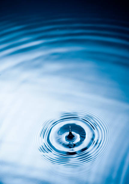 istock Droplet falling and creating ripples on the calm water surface 1073676454