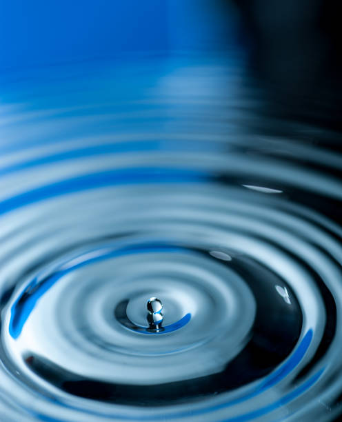 istock Droplet falling and creating ripples on the calm water surface 1073676486