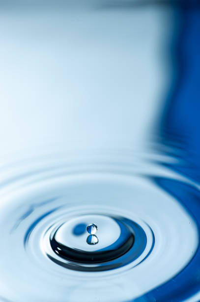 istock Droplet falling and creating ripples on the calm water surface 1073676492