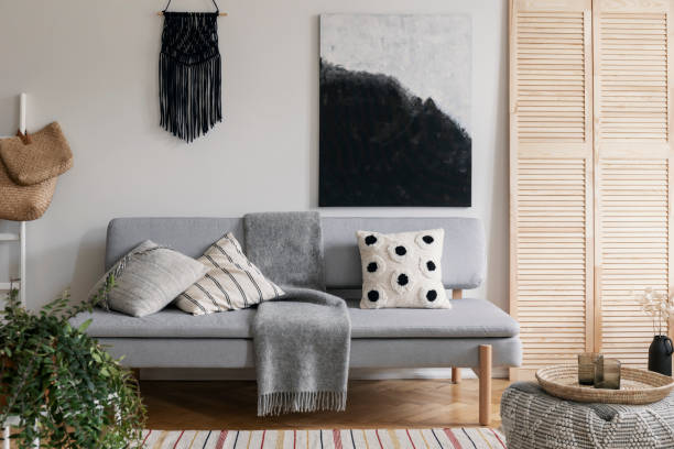 istock Black handmade macrame above grey comfortable couch with pillows and warm blanket, real photo with mockup on the empty wall 1073684418