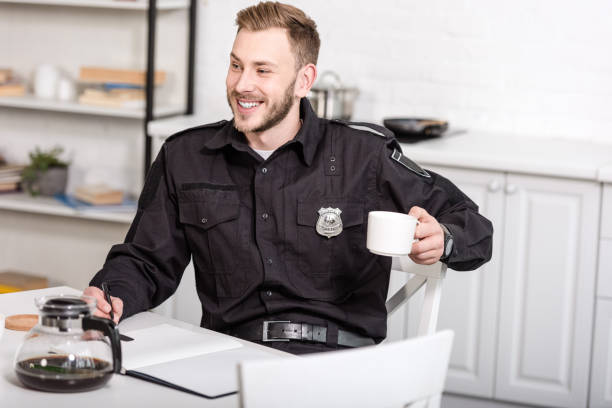 istock smiling police officer sitting at kitchen table, writing in notebook and drinking coffee 1073686178