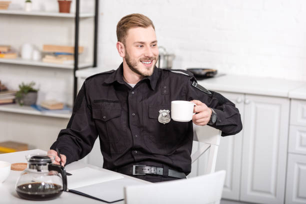 istock handsome police officer sitting at kitchen table, smiling and drinking coffee 1073686202
