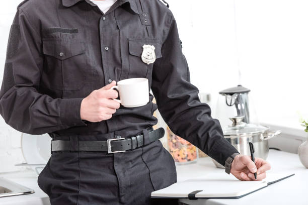 istock police officer drinking coffee and writing in notebook at kitchen table 1073686236
