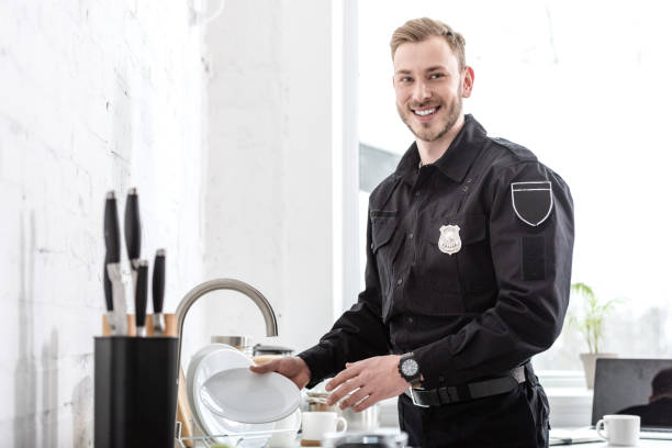 istock Handsome police officer washing dishes at kitchen 1073686246