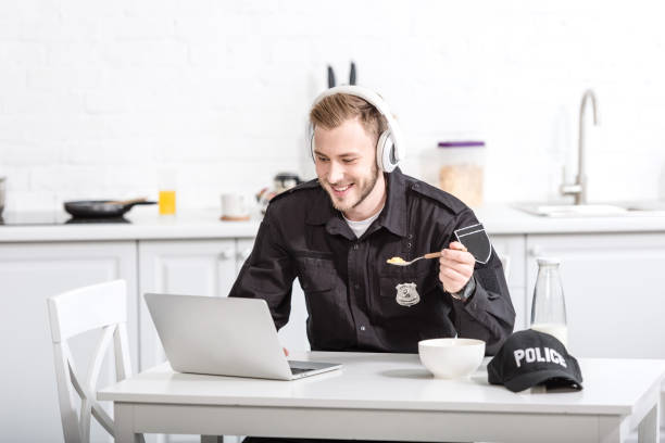 istock Handsome police officer eating cornflakes and using laptop at kitchen 1073686250