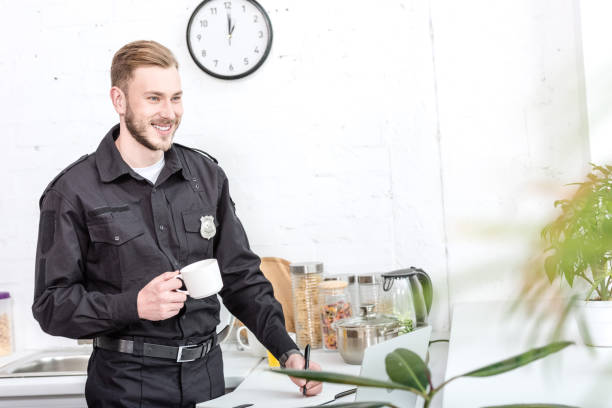 istock Handsome man in police uniform drinking coffee at kitchen 1073686252