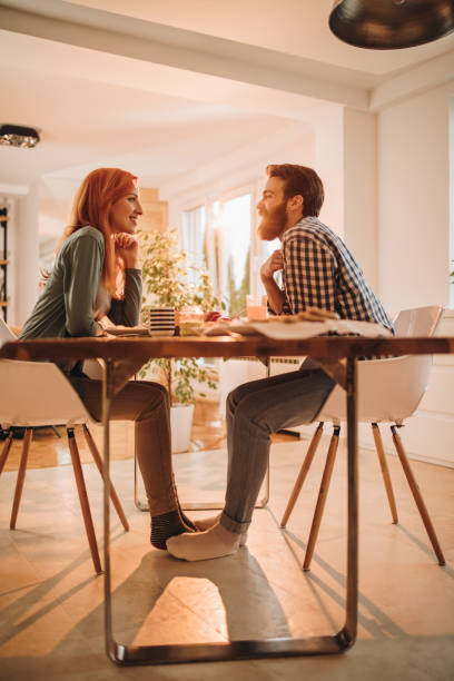 istock Happy couple sitting at dining table at home and communicating during their meal. 1073692136