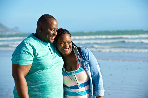 istock Heterosexual African couple walking on the beach hugging 1073692984