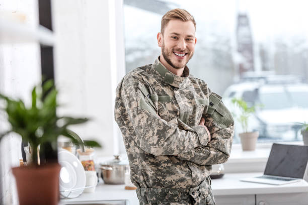 istock handsome soldier smiling and looking at camera in kitchen 1073700172