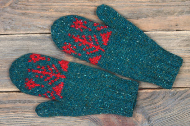 istock Knitted mittens in green on wooden background. 1073701948