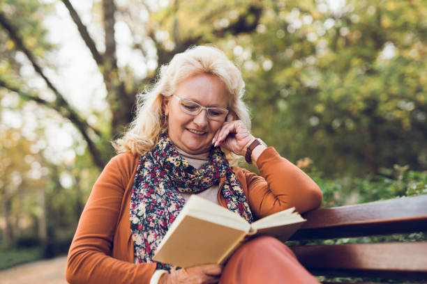istock Senior woman reading a book on park bench 1073706700