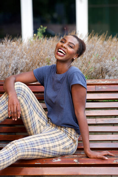 istock young woman sitting on bench outside and laughing 1073707540