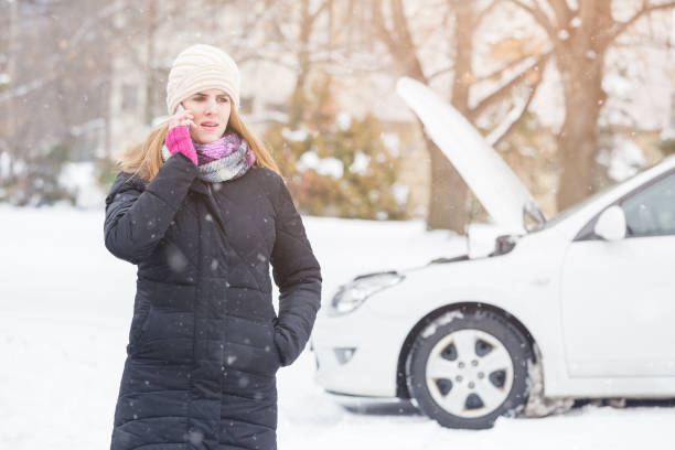 Female standing next to broken car and talking on mobile phone. Young woman using smartphone to call road assistance. Winter and vehicle concept. vehicle breakdown stock pictures, royalty-free photos & images