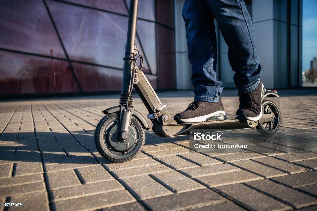 Vista ravvicinata delle gambe dell'uomo su scooter elettrico - Foto stock royalty-free di Monopattino