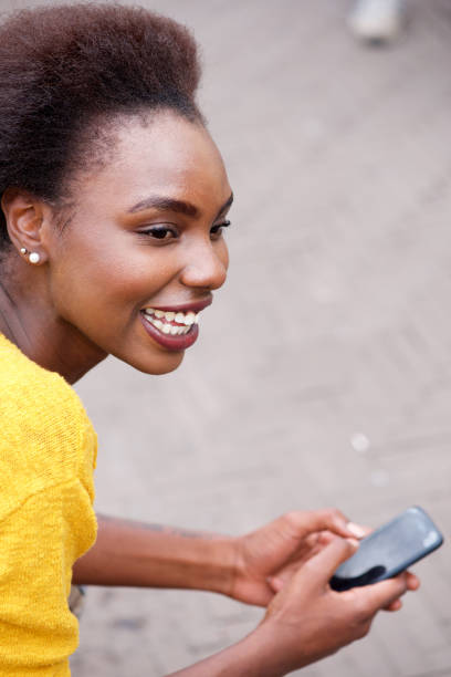 istock smiling young black woman with cellphone outside 1073717798