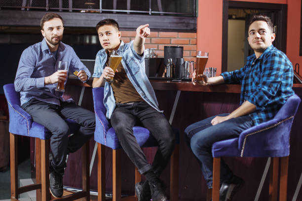 istock Young men with a beer watching the match in the bar. 1073722034