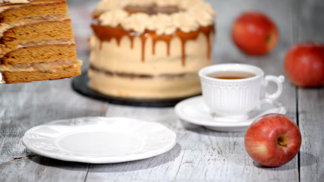 Slice of the caramel apple cake with spices, cinnamon, dried apples, creamy caramel in autumn style.