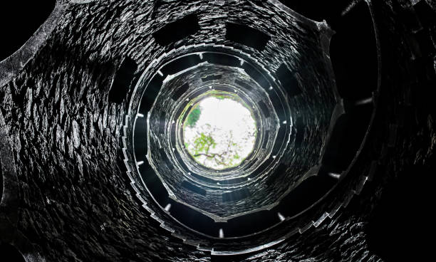 istock a deep cobblestone well / spiral stairs / light coming from top 1073734808