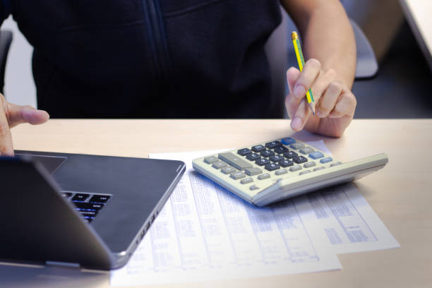 istock Close-up Businessman using calculator and computer laptop for calculating finance on desk table office. financial accounting concept. 1073735174