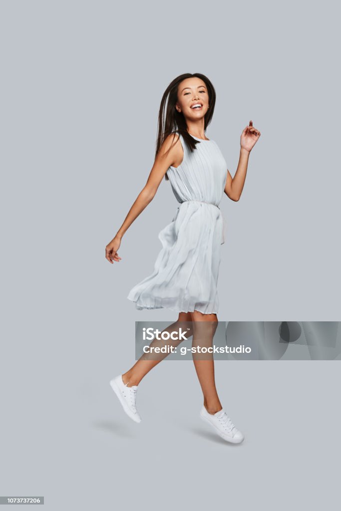 Beautiful perfection. Full length of beautiful young Asian woman smiling and looking at camera while standing against grey background Women Stock Photo