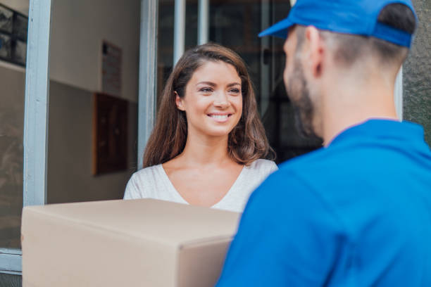 istock Smiling young woman looking at delivery man holding a package 1073737704