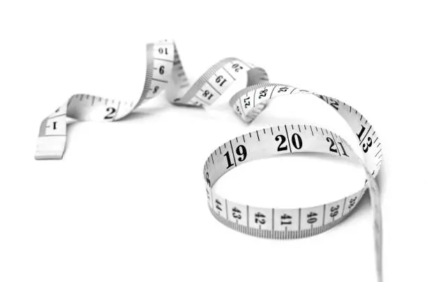 Curly measure tape, dieting or weight loss theme, isolated on white background. Black and white measure tape, top view.