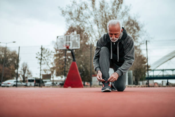 istock Low angle image of senior runner tying shoelaces before a run on stadium. 1073759150