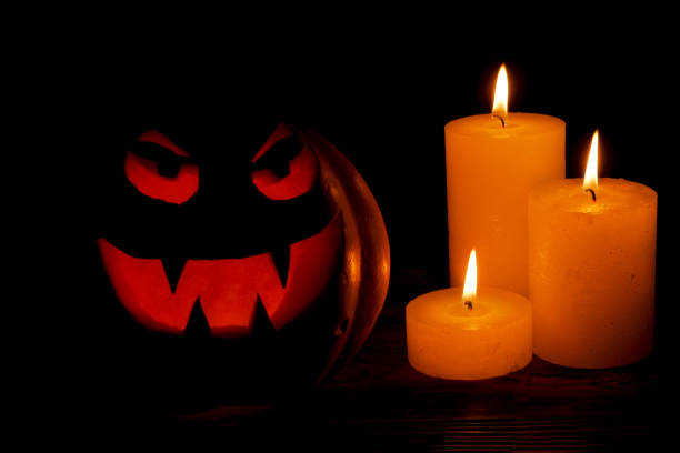 istock Carved Halloween pumpkin lights inside with flame on a black background. Celebration of Halloween. Pumpkin head jack lantern with burning candles in the dark room 1073760262